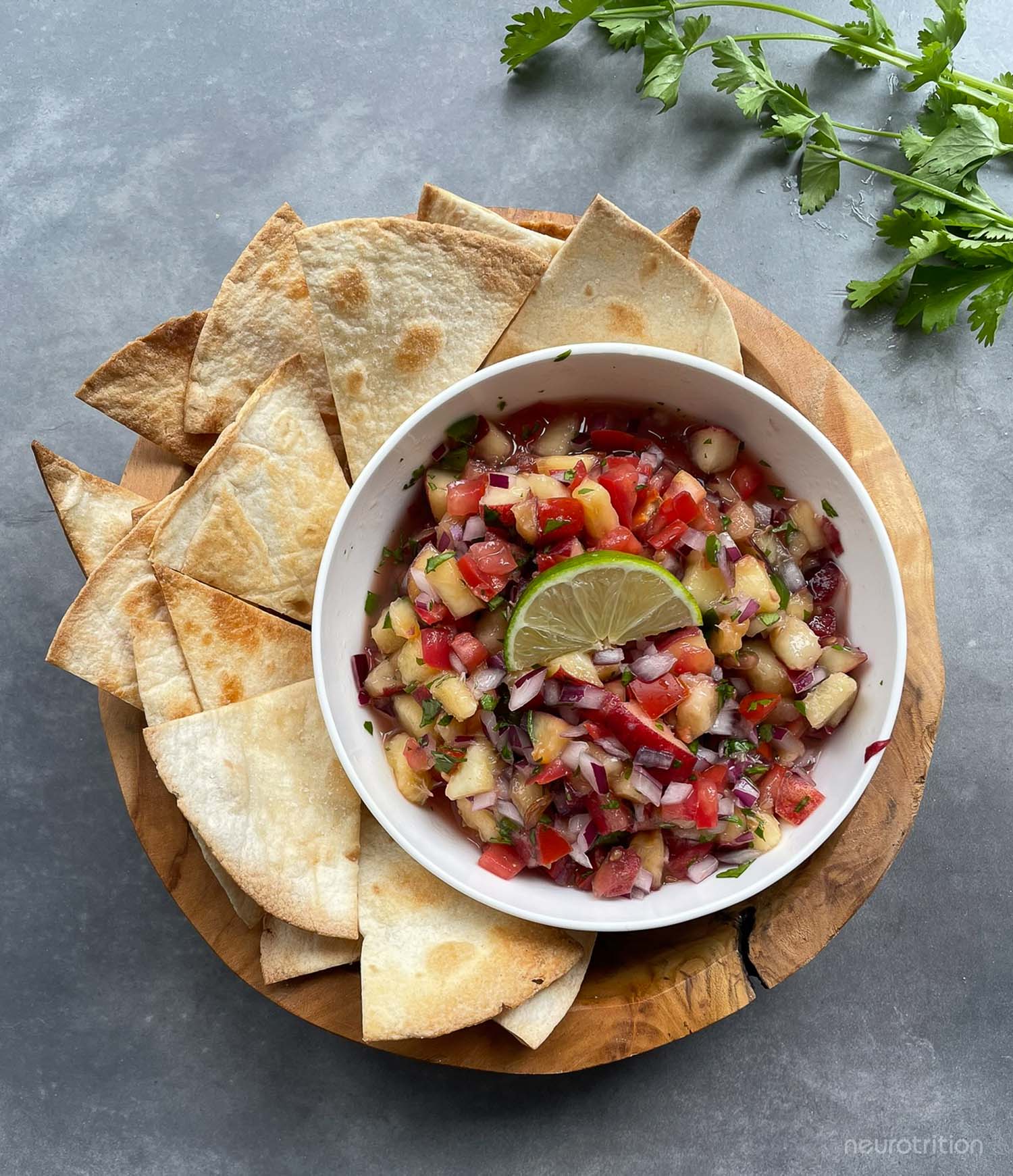 Fresh Stone Fruit Salsa A bowl of homemade salsa is surrounded by baked pita chips on a wooden tray.