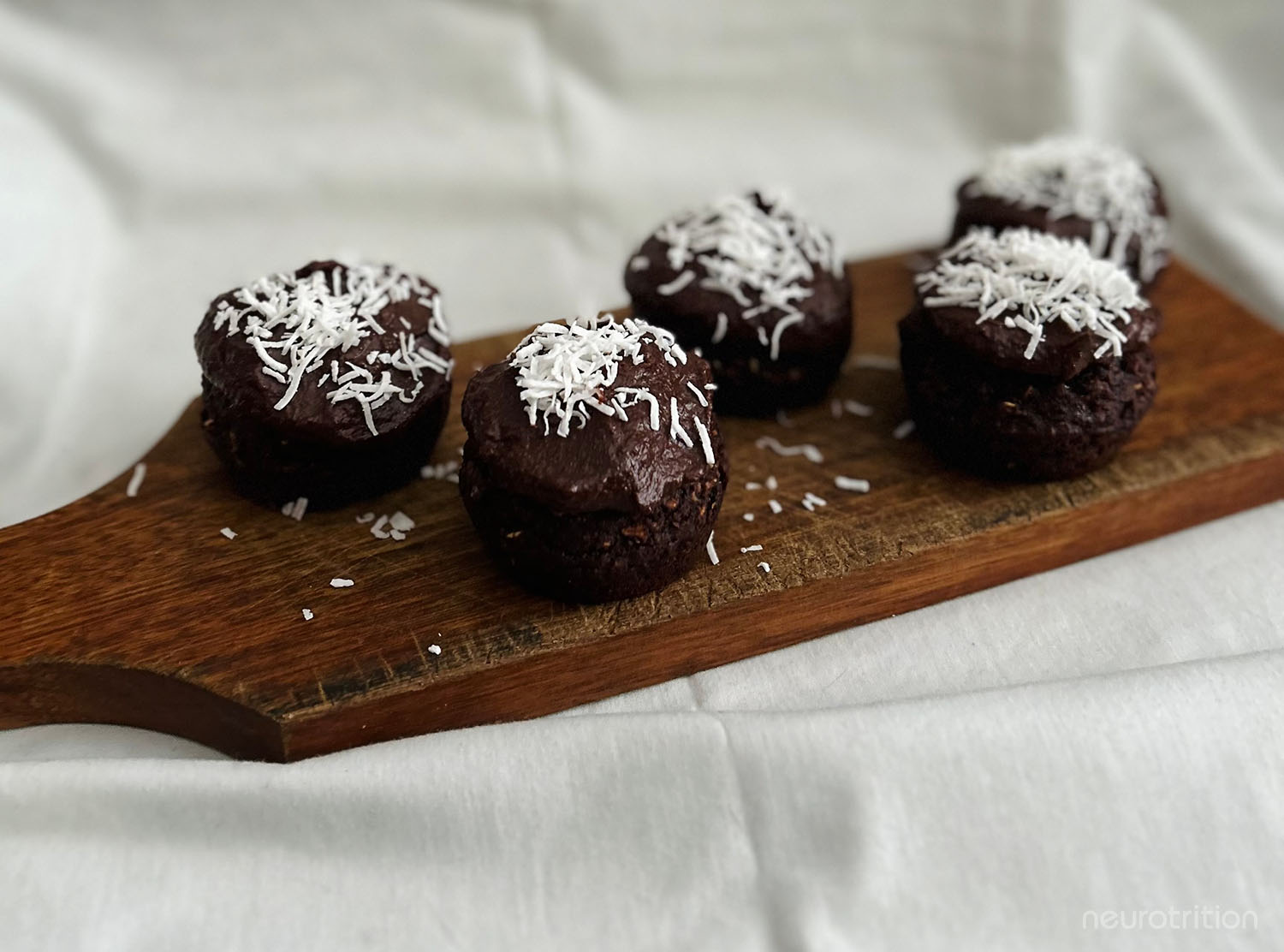 Fudgy Chocolate Cupcakes with Sweet Potato Frosting Fudgy chocolate cupcakes with sweet potato frosting topped with shredded coconut on wooden cutting board.