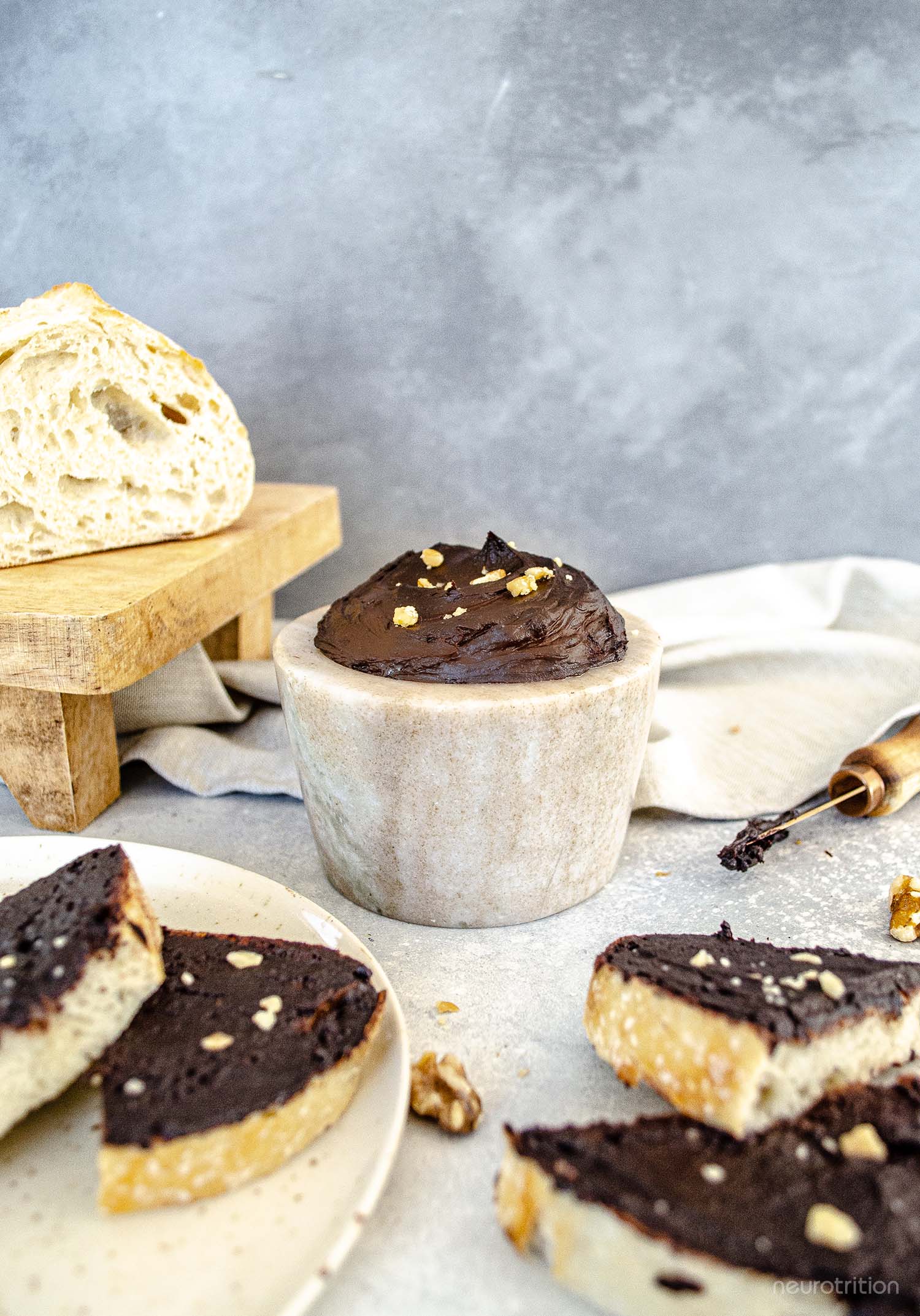 Simple Neuro-Nutella A stone dish full of homemade chocolate spread is surrounded by slices of bread that are covered in the chocolate spread and topped with crushed walnuts.