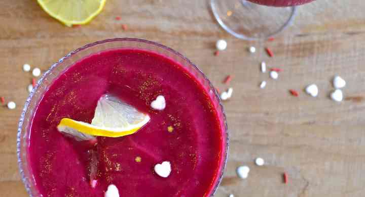 Two bright pink smoothies in cocktail glasses, with lemon twists and heart and star sprinkles.